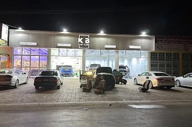 واجهة مركز KB للعناية بالسيارات ليلا وأمامها سيارات